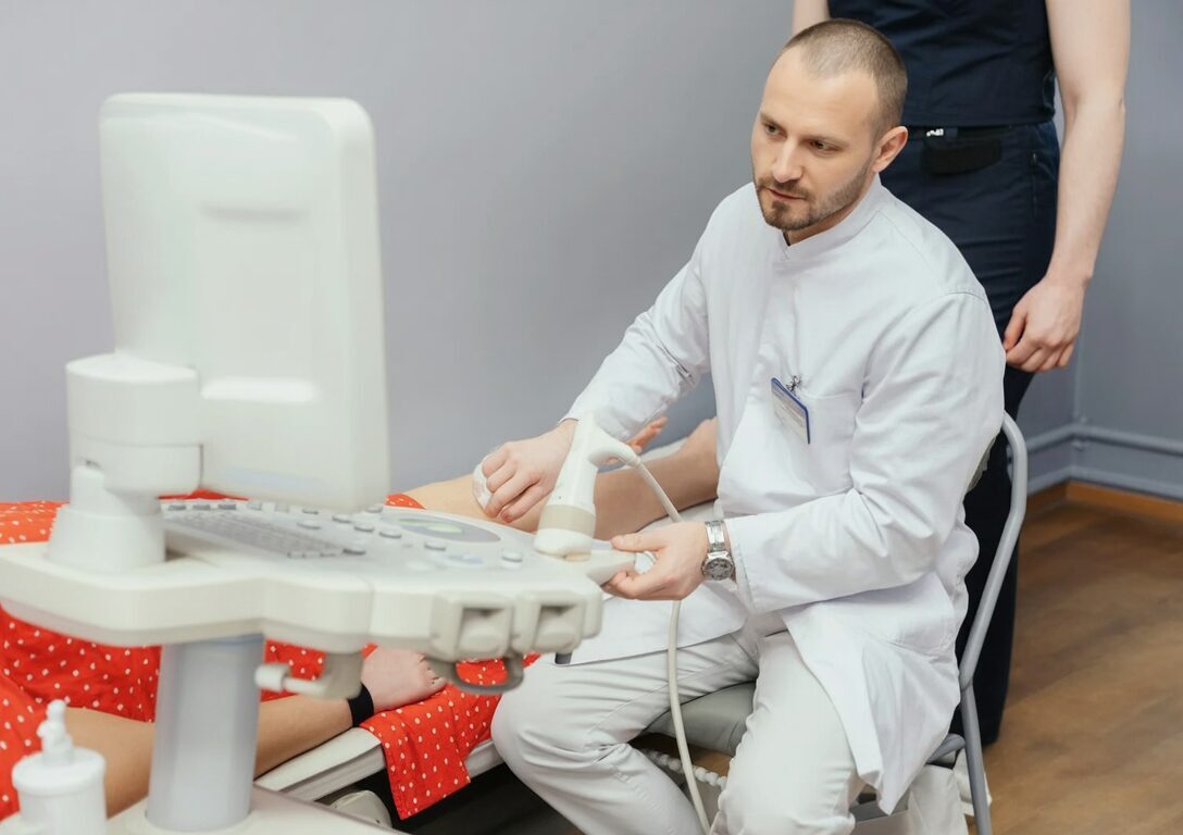 Врач проводит УЗ-оценку коленного сустава